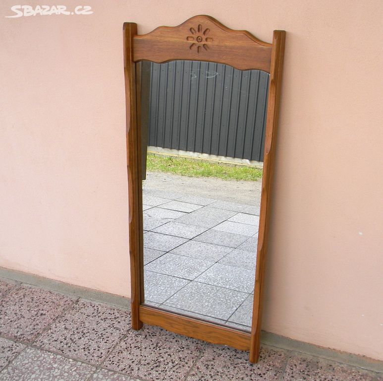 Nástěnné zrcadlo v dřevěném rámu.